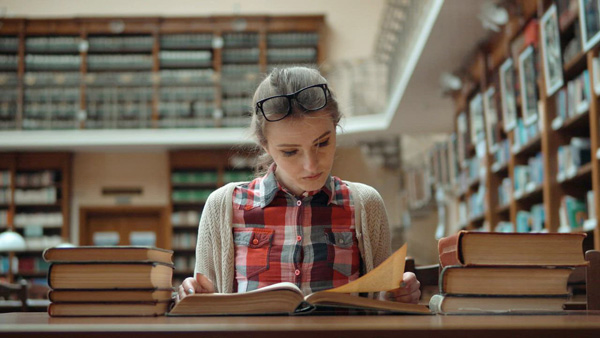 mixkit-student-stressed-over-exam-sits-with-books-in-library-8926-0.jpg